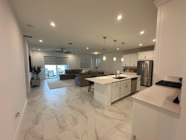 10230 SW Orana Dr, Port Saint Lucie, FL 34987 - kitchen featuring stainless steel appliances, a sink, baseboards, open floor plan, and white cabinetry
