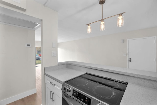 5821 Washington St Unit 21, Hollywood, FL 33023 - kitchen with stainless steel electric stove, white cabinets, light wood-type flooring, baseboards, and pendant lighting