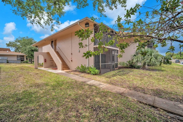 5821 Washington St Unit 21, Hollywood, FL 33023 - rear view of house featuring stucco siding, stairs, a yard, and a sunroom