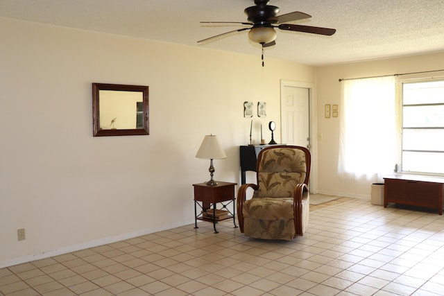 living area with ceiling fan, baseboards, and light tile patterned floors