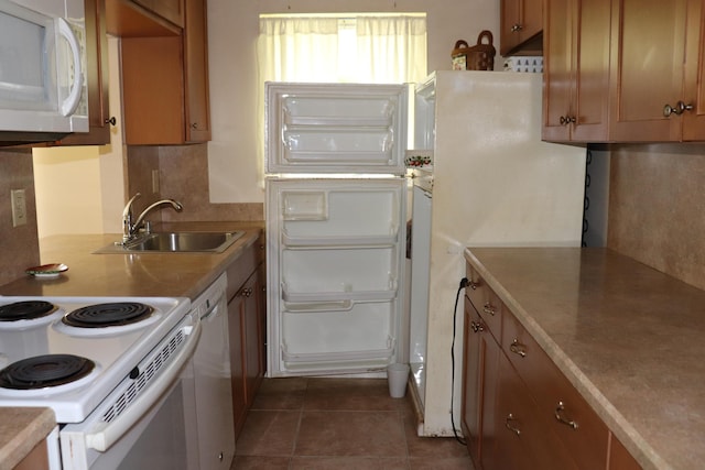 kitchen with brown cabinets, white appliances, and a sink