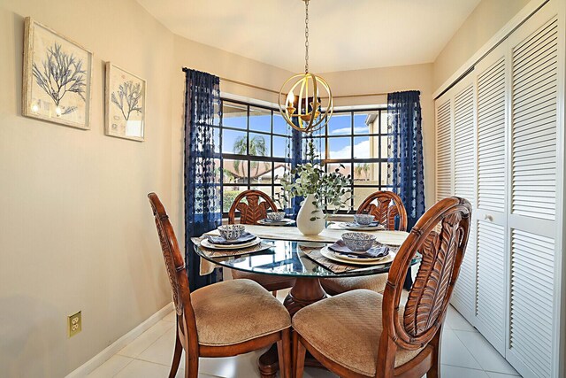 dining space featuring a chandelier, tile patterned floors, and baseboards