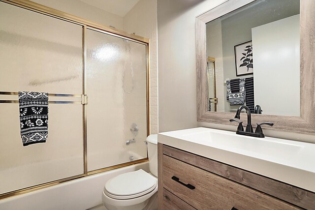full bath featuring toilet, shower / bath combination with glass door, and vanity