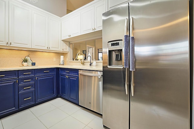 kitchen featuring appliances with stainless steel finishes, blue cabinetry, light countertops, and white cabinetry