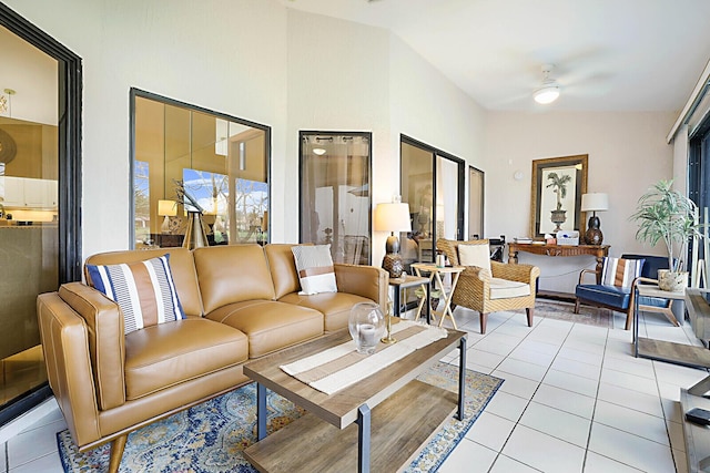 living room featuring tile patterned flooring, a ceiling fan, plenty of natural light, and a high ceiling