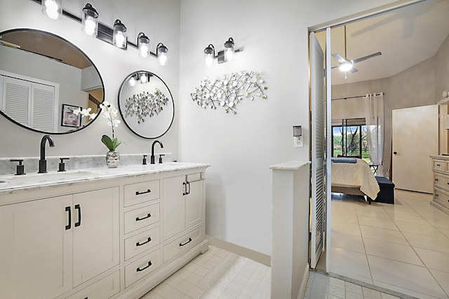 ensuite bathroom with double vanity, ceiling fan, tile patterned flooring, and baseboards