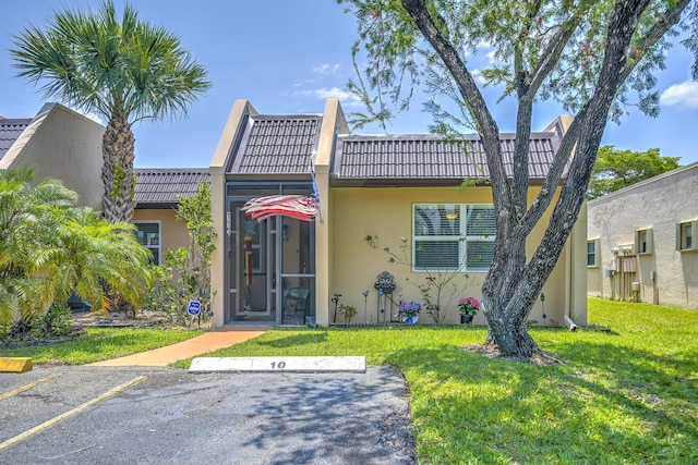 rear view of house with a yard, stucco siding, and uncovered parking