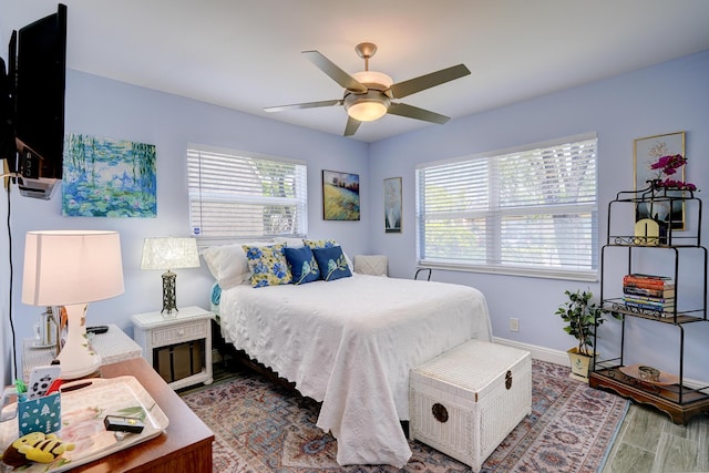 bedroom with a ceiling fan, wood finished floors, and baseboards