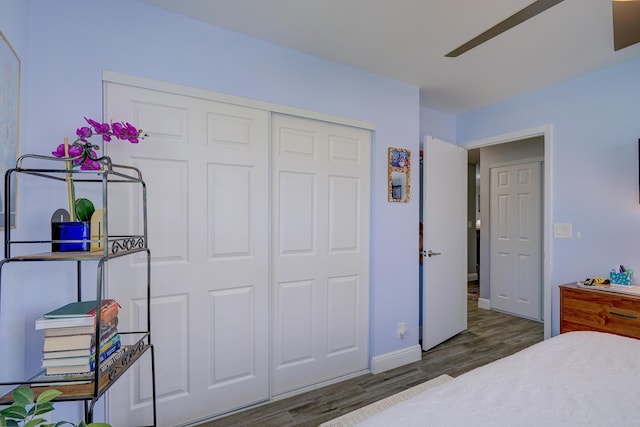 bedroom with a closet, wood finished floors, and baseboards