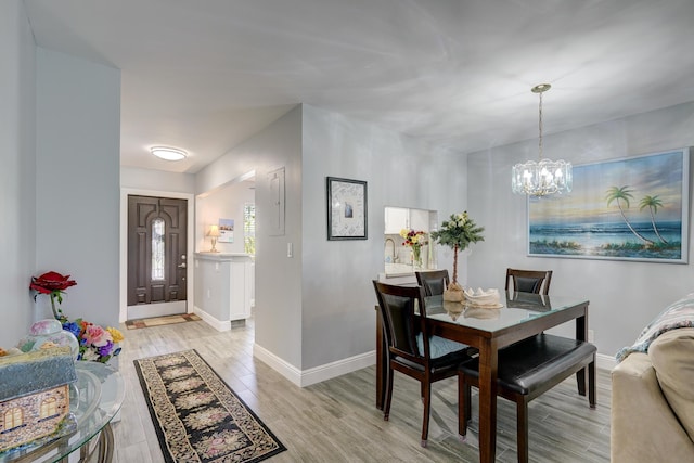 dining area with light wood-style floors, baseboards, and a notable chandelier