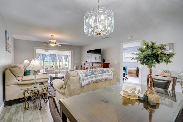 dining room with light wood-style flooring and ceiling fan with notable chandelier