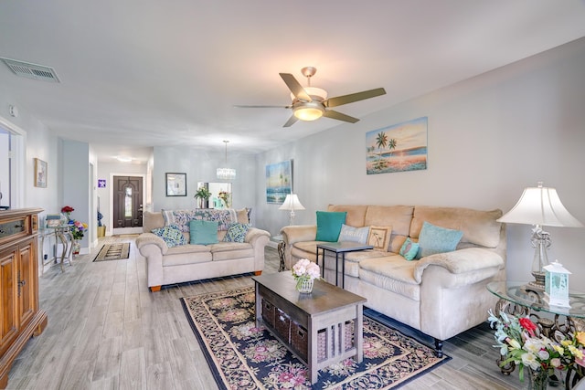 living area with light wood-type flooring, visible vents, baseboards, and a ceiling fan