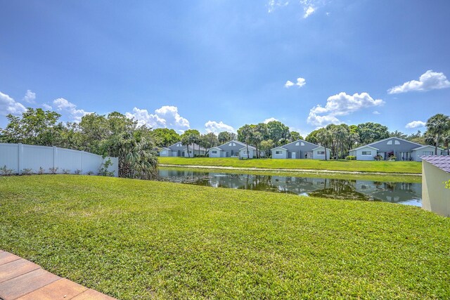view of yard featuring a water view, a residential view, and fence