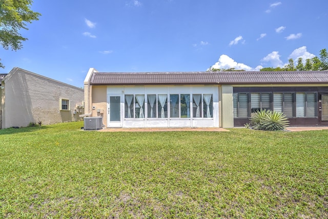rear view of house with central AC unit and a yard
