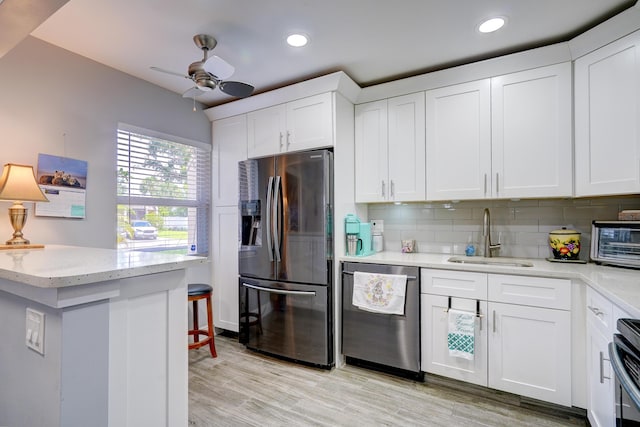 kitchen featuring a sink, white cabinetry, ceiling fan, appliances with stainless steel finishes, and decorative backsplash