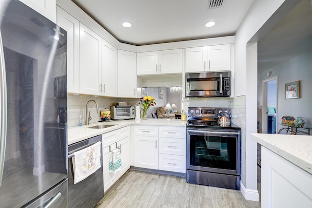 kitchen with appliances with stainless steel finishes, visible vents, tasteful backsplash, and a sink