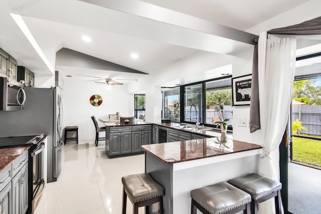 kitchen with a sink, stainless steel microwave, a peninsula, a breakfast bar area, and electric range