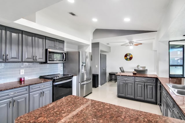 kitchen with lofted ceiling, light tile patterned floors, ceiling fan, backsplash, and stainless steel appliances