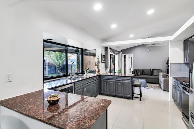 kitchen featuring recessed lighting, a sink, open floor plan, dark stone countertops, and a peninsula