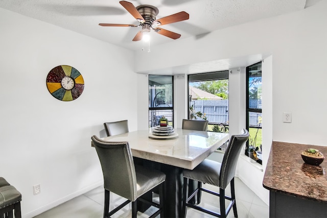 dining area featuring a textured ceiling, baseboards, a ceiling fan, and light tile patterned floors