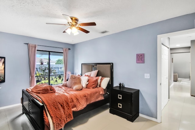 bedroom featuring a textured ceiling, visible vents, baseboards, and ceiling fan