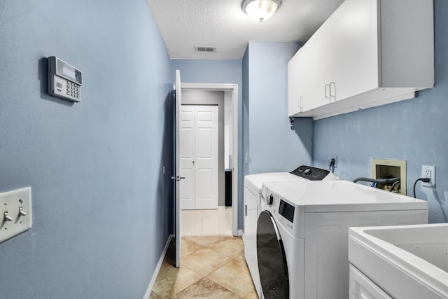 clothes washing area with cabinet space, a textured ceiling, visible vents, washing machine and dryer, and baseboards