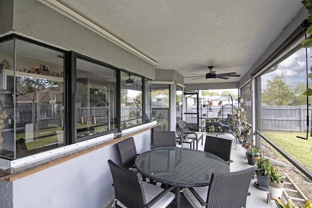 sunroom featuring outdoor dining area and a ceiling fan