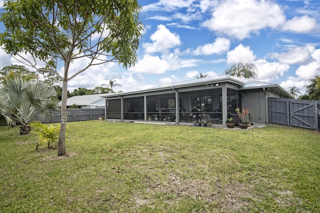 back of house featuring a sunroom, a yard, a gate, and a fenced backyard