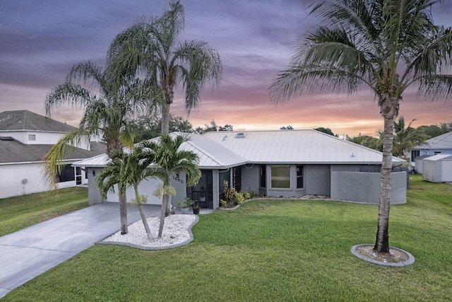 view of front facade featuring an attached garage, stucco siding, metal roof, concrete driveway, and a front yard
