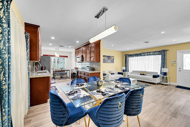 dining room with healthy amount of natural light, light wood-style floors, recessed lighting, and baseboards