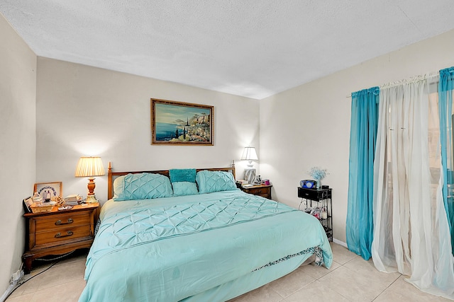 bedroom featuring tile patterned floors, a textured ceiling, and baseboards