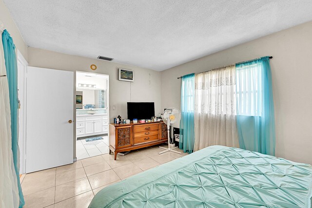 bedroom with light tile patterned floors, a textured ceiling, and connected bathroom