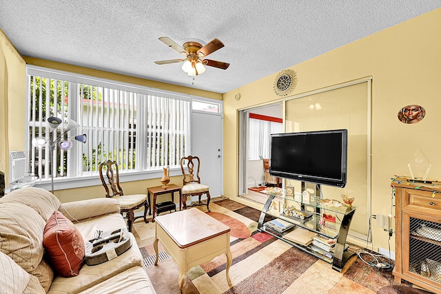 living area with ceiling fan and a textured ceiling