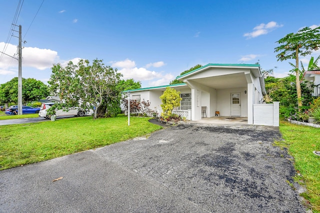 view of front of home featuring asphalt driveway, a front lawn, stucco siding, and an attached carport