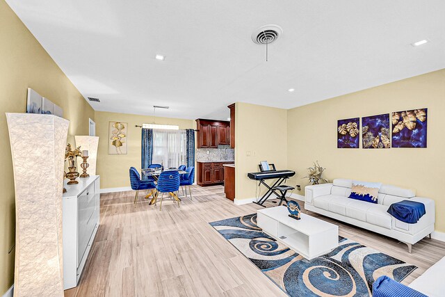living room featuring light wood-style floors, baseboards, and recessed lighting