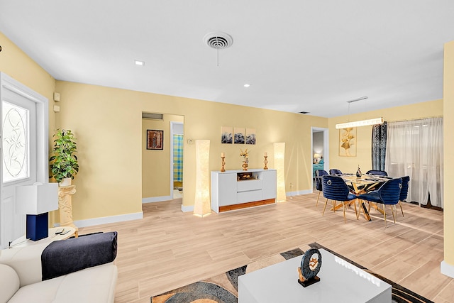 living area with baseboards, light wood-type flooring, and recessed lighting