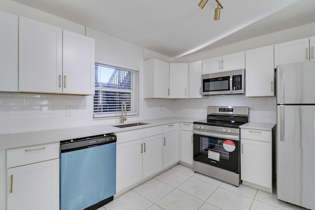 kitchen with stainless steel appliances, a sink, white cabinetry, light countertops, and tasteful backsplash
