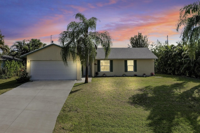 single story home featuring an attached garage, driveway, stucco siding, and a front yard