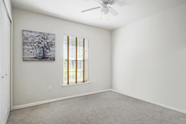 empty room with carpet flooring, a ceiling fan, and baseboards