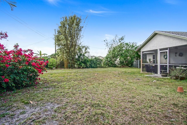 view of grassy yard with a sunroom