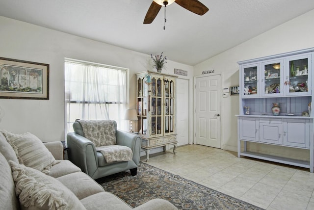 living area featuring ceiling fan, lofted ceiling, and light tile patterned floors