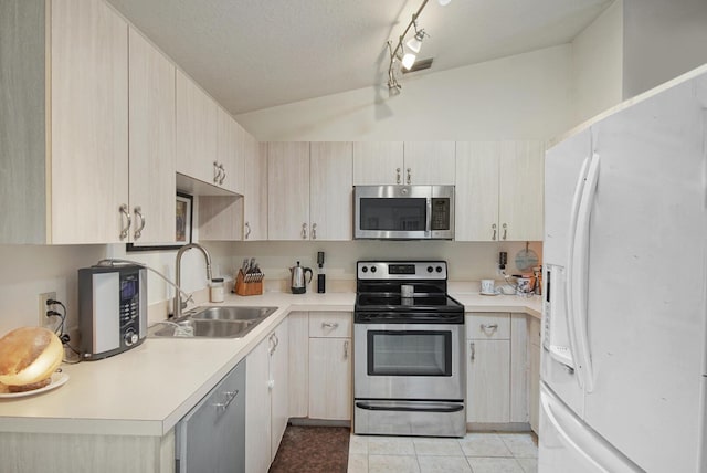 kitchen featuring stainless steel appliances, a sink, lofted ceiling, light countertops, and light tile patterned flooring