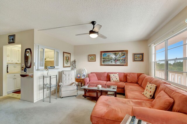 living room featuring light colored carpet, a ceiling fan, and a textured ceiling