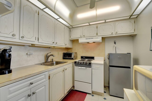 kitchen with freestanding refrigerator, electric range oven, under cabinet range hood, a sink, and light countertops