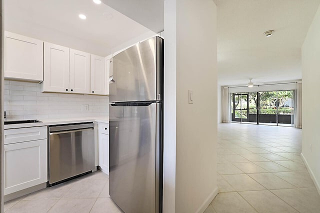kitchen featuring stainless steel appliances, baseboards, light tile patterned flooring, backsplash, and white cabinets