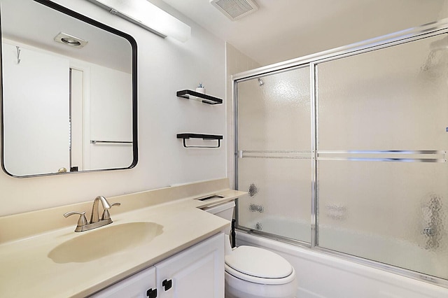 bathroom with toilet, vanity, and bath / shower combo with glass door