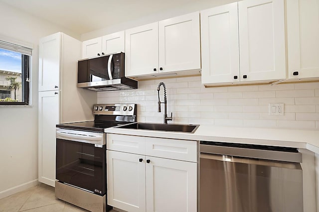 kitchen featuring appliances with stainless steel finishes, a sink, tasteful backsplash, and white cabinets