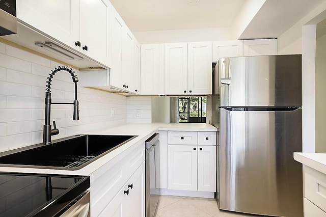 kitchen with appliances with stainless steel finishes, a sink, light countertops, and white cabinets