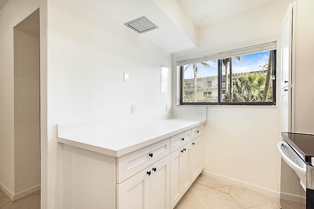 kitchen featuring baseboards, white cabinetry, light tile patterned flooring, and light countertops
