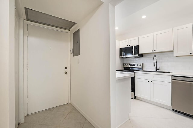 kitchen featuring stainless steel appliances, a sink, backsplash, white cabinets, and recessed lighting